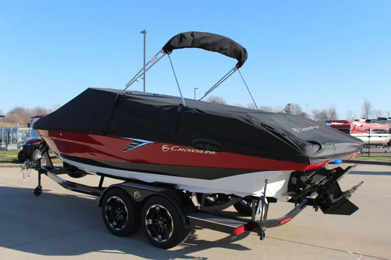 Slide: The Image of 2024 Crownline 240 SS boat with cover on trailer, parked outdoors. - 15