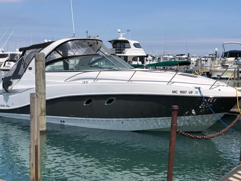 The Image of 2013 Rinker 310 Express Cruiser docked in a marina, surrounded by other boats. - 0