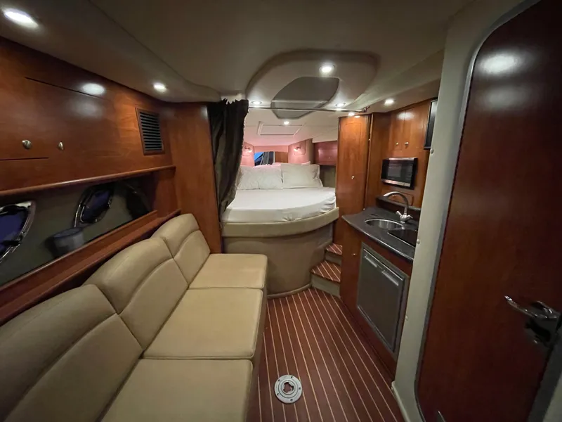 Slide: The Image of 2013 Rinker 310 Express Cruiser interior with cozy seating, kitchenette, and bed. - 25