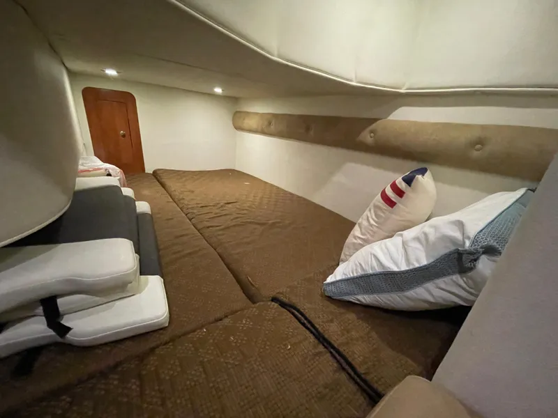 Slide: The Image of 2013 Rinker 310 Express Cruiser cabin interior with cozy bedding and cushions. - 35