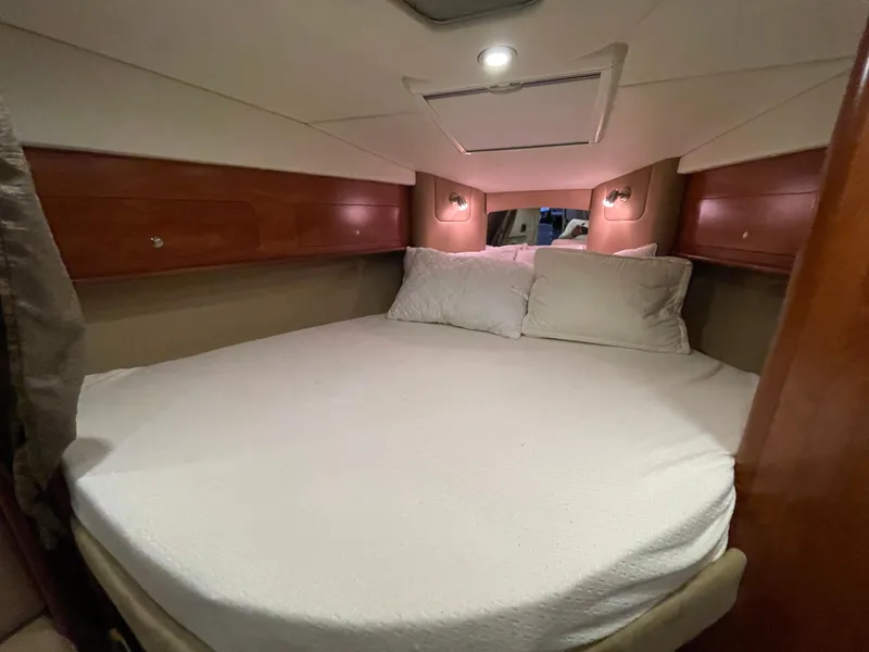 Slide: The Image of 2013 Rinker 310 Express Cruiser cabin with cozy bed and ambient lighting. - 36