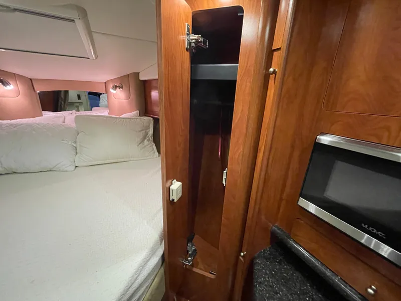 Slide: The Image of 2013 Rinker 310 Express Cruiser interior with bed, wooden cabinetry, and microwave. - 37