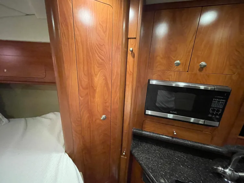 Slide: The Image of 2013 Rinker 310 Express Cruiser interior with wood cabinetry and microwave. - 38