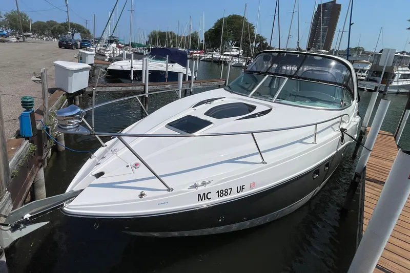 Slide: The Image of 2013 Rinker 310 Express Cruiser docked at a marina, surrounded by other boats. - 6