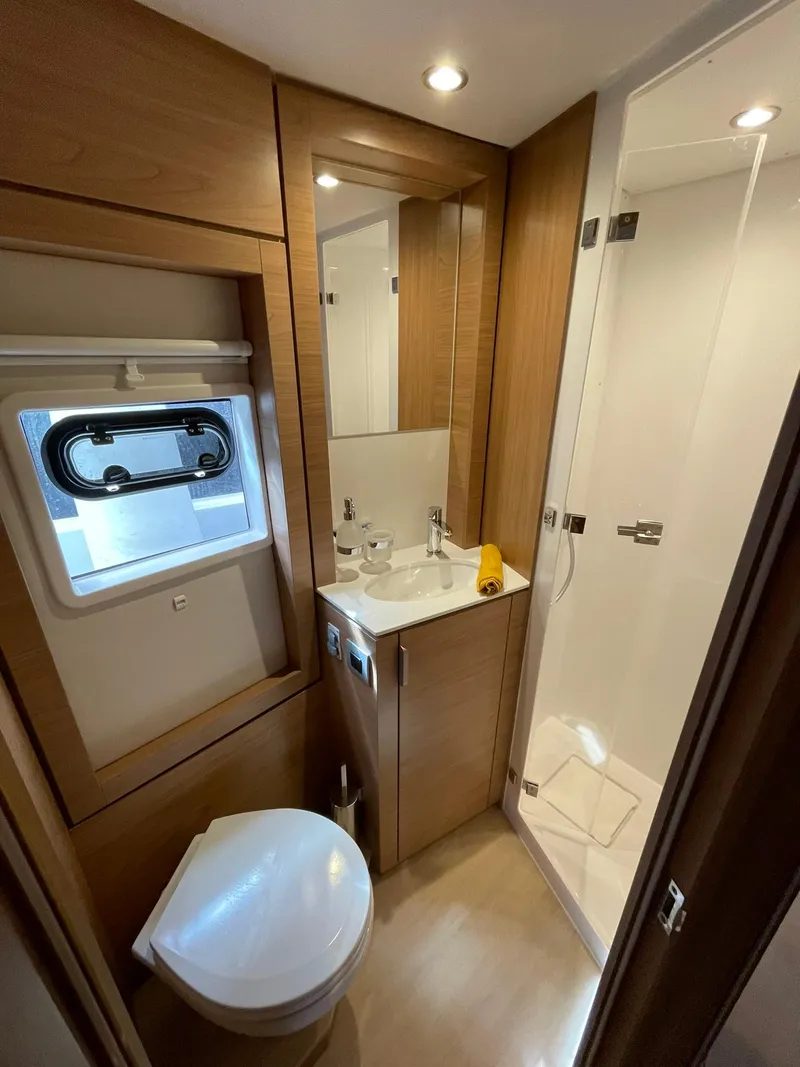 Slide: The Image of Modern yacht bathroom with wood accents, featuring a toilet, sink, and shower in a Bali 4.4 model. - 23
