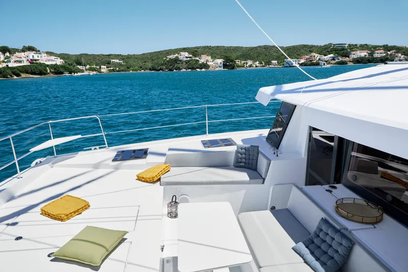 Slide: The Image of Luxurious Bali 4.4 yacht deck with cushions, overlooking serene blue waters and coastal scenery. - 35