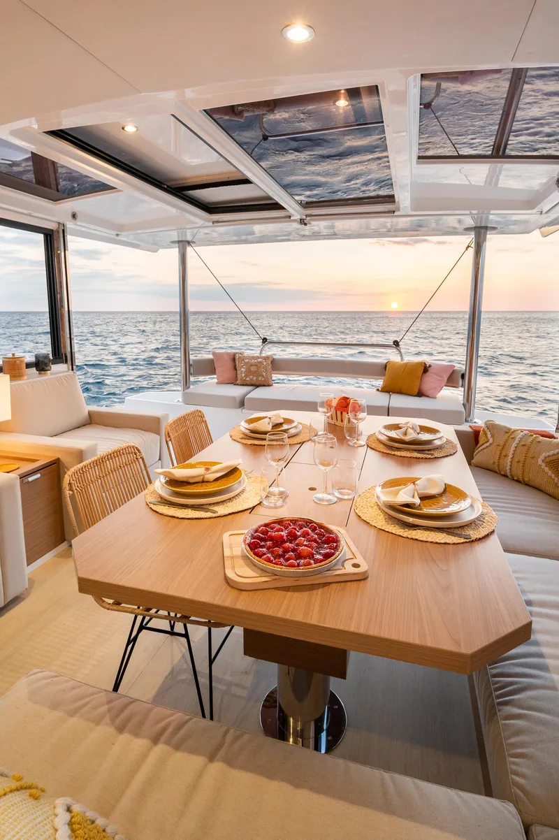 Slide: The Image of Luxurious Bali 4.4 yacht interior with dining setup, ocean view, and sunset ambiance, 2026 model. - 8