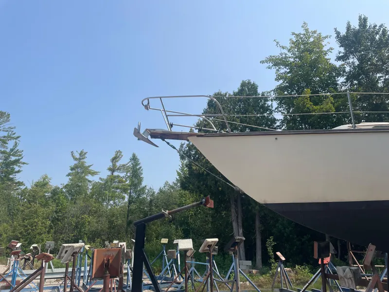 Slide: The Image of 1980 Cape Dory 36 sailboat on stands, surrounded by trees under a clear blue sky. - 3