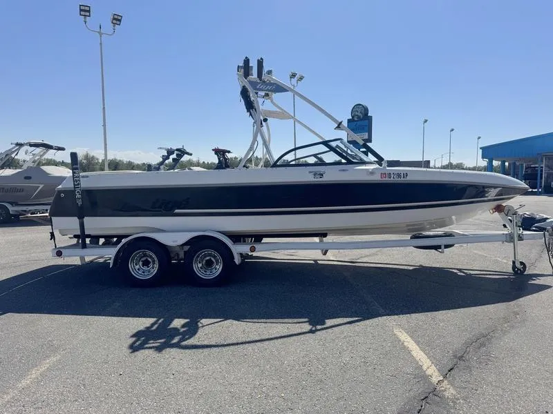 The Image of 2002 Tigé 2300V Limited boat on trailer in parking lot, sunny day. - 0