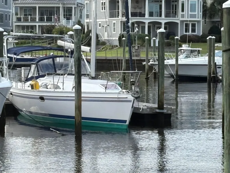 Slide: The Image of Sailboat Catalina 355, 2011 model, docked in a marina with waterfront homes in the background. - 2