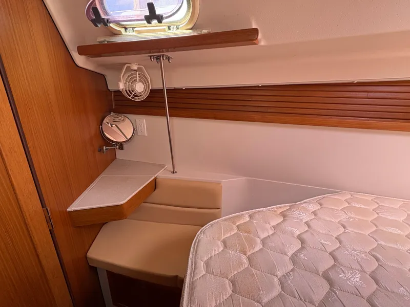 Slide: The Image of 2011 Catalina 355 yacht interior with wooden paneling, small fan, and mattress. - 32