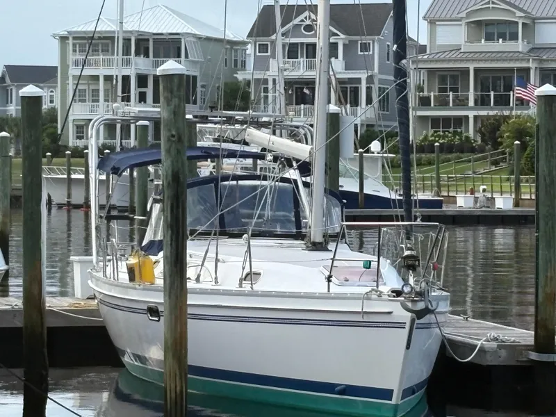 Slide: The Image of Sailboat Catalina 355, 2011 model, docked in a marina with waterfront homes in the background. - 44