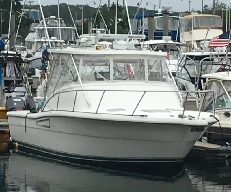 Slide: The Image of 1996 Pursuit 3000 Offshore boat docked in a marina, surrounded by other vessels. - 1
