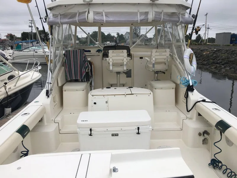 Slide: The Image of 1996 Pursuit Offshore boat interior with seating, fishing gear, and Yeti cooler at dock. - 2