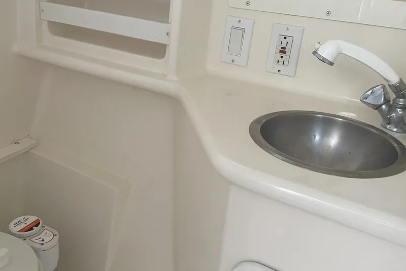 Slide: The Image of 1996 Pursuit Offshore boat bathroom with sink, faucet, and electrical outlets. - 6