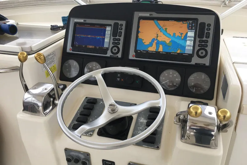 Slide: The Image of Control panel of a 1996 Pursuit 3000 Offshore boat with navigation screens and steering wheel. - 9