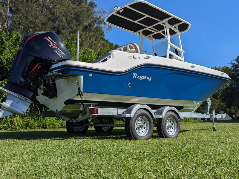 Slide: The Image of 2025 Bayliner Trophy T20CC boat on trailer, blue hull, outboard motor, grassy background. - 12