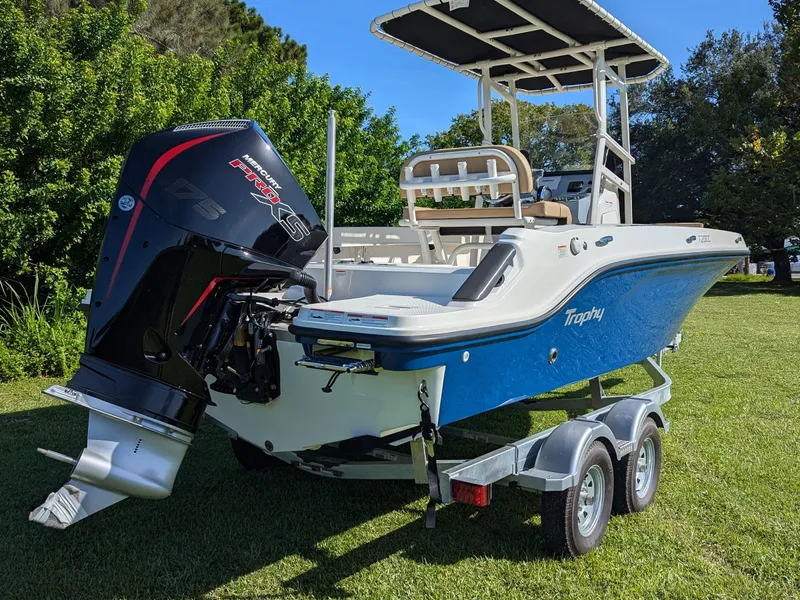 Slide: The Image of 2025 Bayliner Trophy T20CC boat on trailer with Mercury engine, parked on grass. - 13