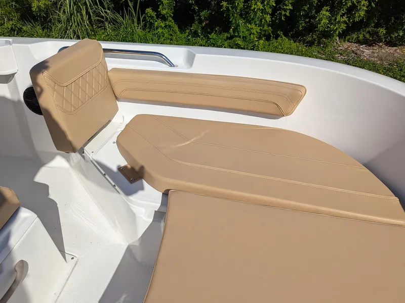 Slide: The Image of 2025 Bayliner Trophy T20CC boat interior with tan seating and lush greenery background. - 20