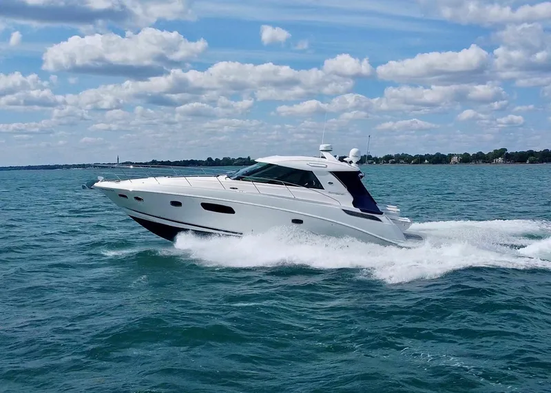 Slide: The Image of 2010 Sea Ray 450 Sundancer cruising on open water under a partly cloudy sky. - 4