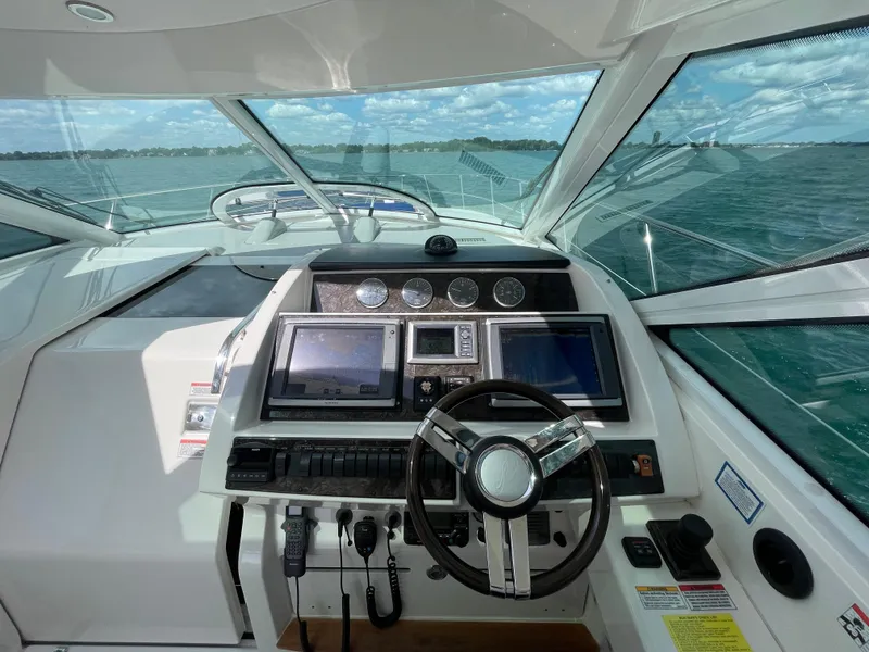 Slide: The Image of Helm of 2010 Sea Ray 450 Sundancer with navigation screens and steering wheel, overlooking ocean. - 46