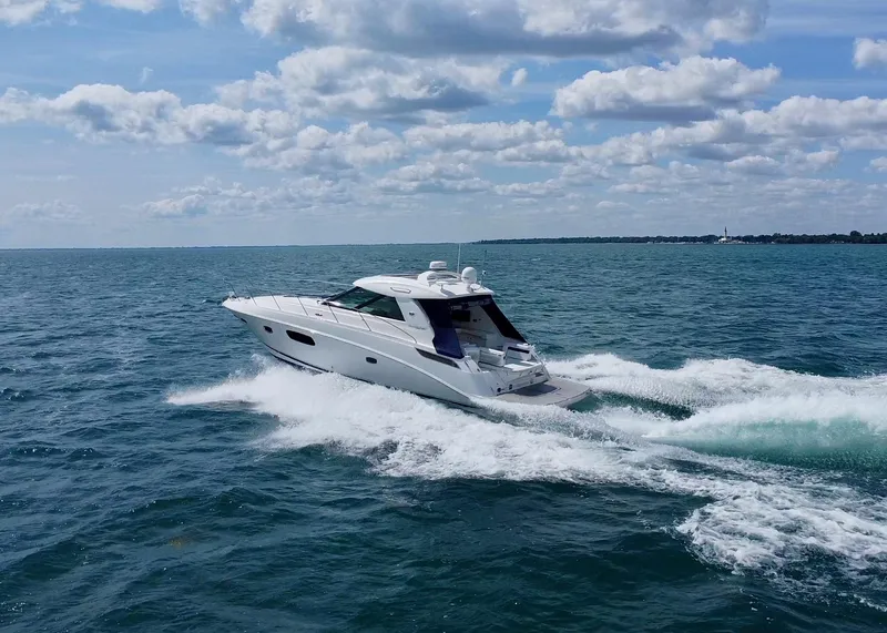 Slide: The Image of 2010 Sea Ray 450 Sundancer cruising on open water under a partly cloudy sky. - 6