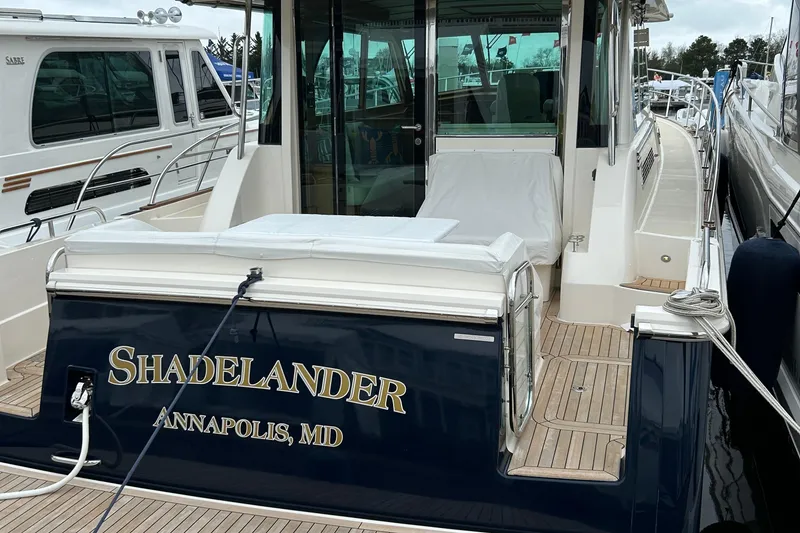 Slide: The Image of 2022 Sabre 45 Salon Express boat on water near shoreline with trees. - 2