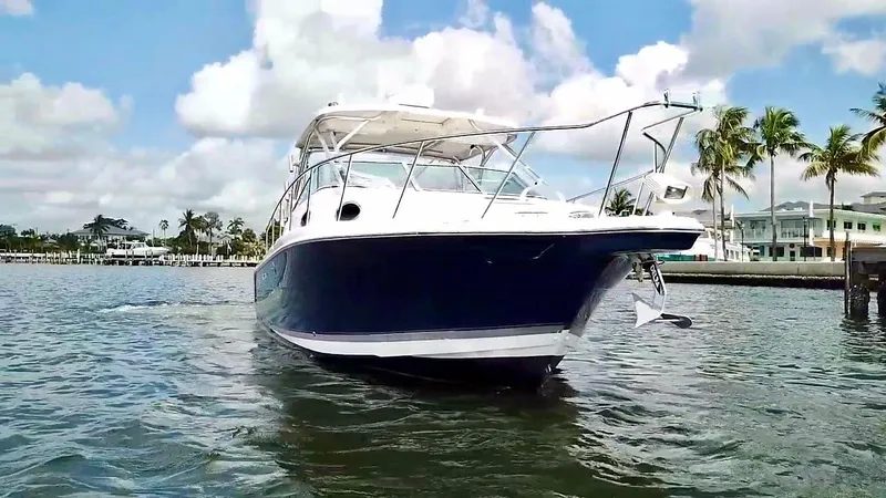 Slide: The Image of 2005 Wellcraft 290 Coastal boat on water, with palm trees and buildings in background. - 5