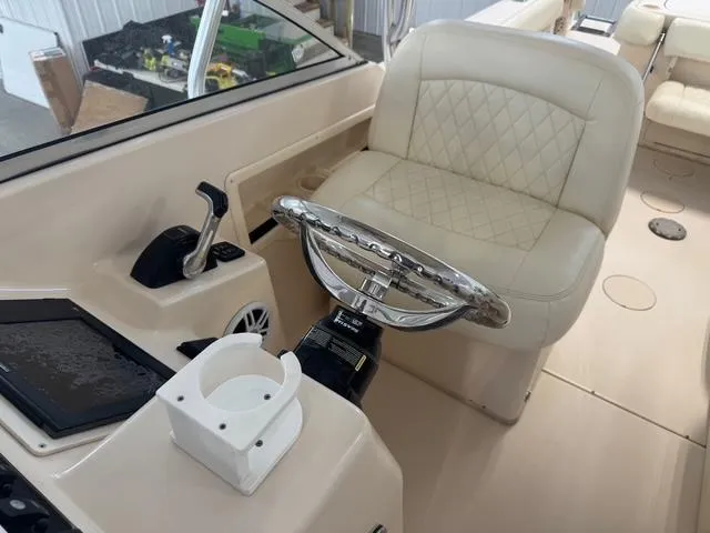 Slide: The Image of Captain's seat and helm of 2011 Grady-White Freedom 275 boat, featuring steering wheel and controls. - 14