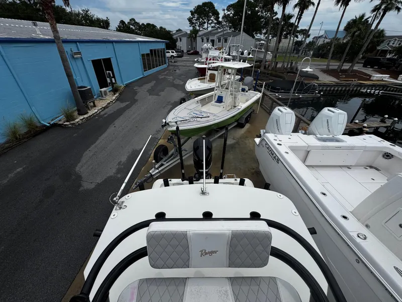 Slide: The Image of 2023 Ranger 2510 Bay boat in marina, surrounded by other boats and a blue building. - 23