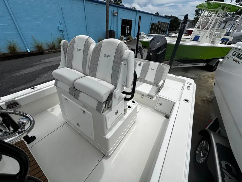 Slide: The Image of 2023 Ranger 2510 Bay boat interior with white seating and steering wheel, parked outdoors. - 25