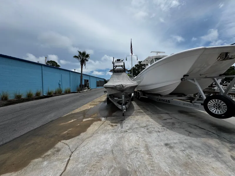 Slide: The Image of 2023 Ranger 2510 Bay boat on trailer near blue building and palm tree. - 28