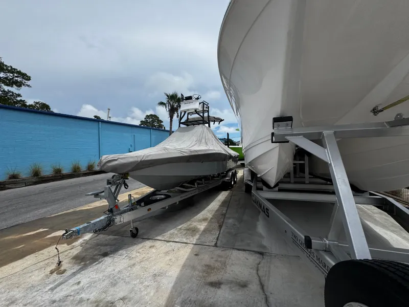 Slide: The Image of 2023 Ranger 2510 Bay boat on trailer, covered, beside another boat, outdoors. - 29