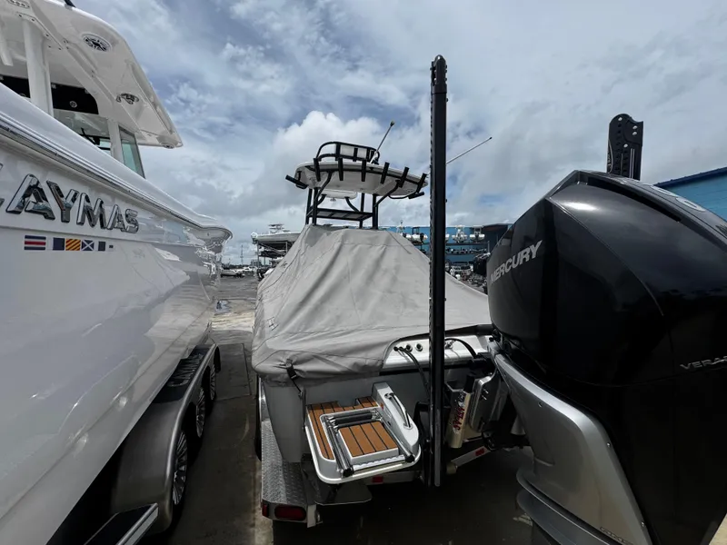 Slide: The Image of 2023 Ranger 2510 Bay boat with Mercury engine, covered and docked beside another vessel. - 30