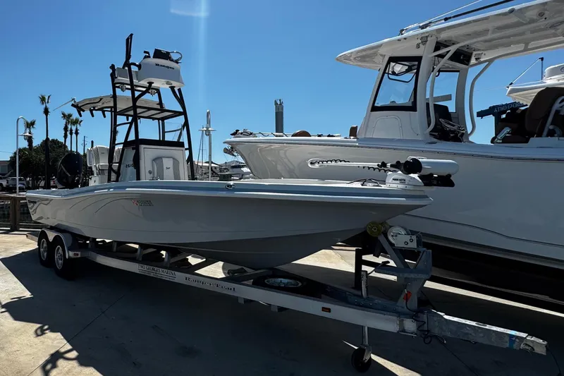 Slide: The Image of 2023 Ranger 2510 Bay boat on trailer, parked beside another boat under clear blue sky. - 4
