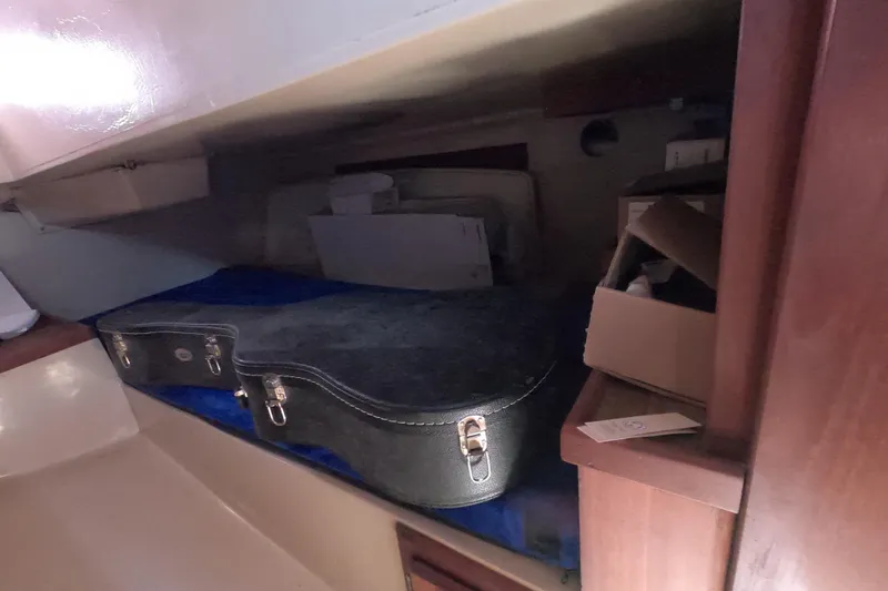 Slide: The Image of Storage area inside a 1983 Catalina 36 sailboat with a guitar case and boxes. - 14