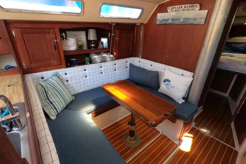 Slide: The Image of Cozy 1983 Catalina 36 sailboat interior with wooden table, cushioned seating, and nautical decor. - 18