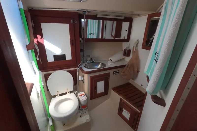 Slide: The Image of 1983 Catalina 36 yacht bathroom with toilet, sink, mirror, and towel. - 23