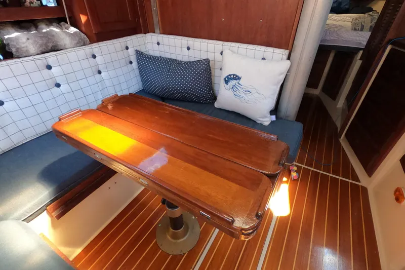 Slide: The Image of Cozy 1983 Catalina 36 sailboat interior with wooden table and cushioned seating. - 25