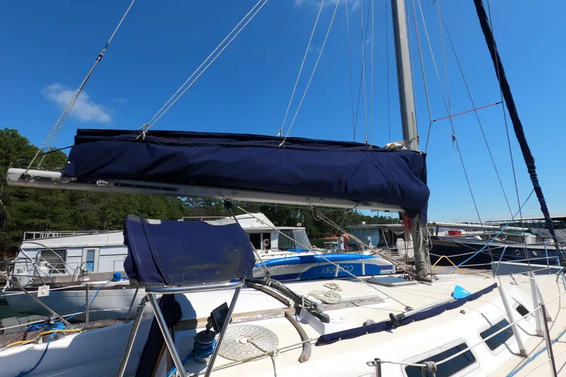 Slide: The Image of 1983 Catalina 36 sailboat with blue sail cover docked at marina under clear sky. - 27