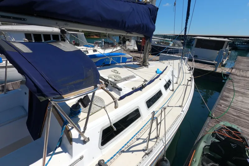 Slide: The Image of 1983 Catalina 36 sailboat docked at marina, featuring blue canvas covers and white deck. - 4