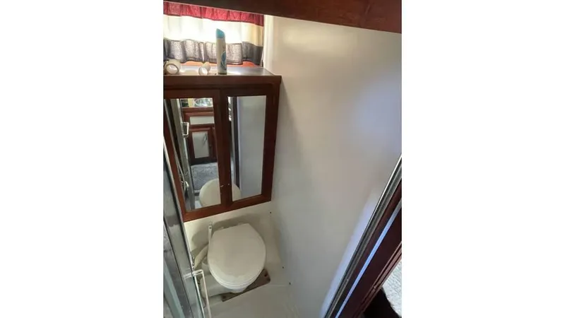 Slide: The Image of 1986 Carver 3607 Aft Cabin bedroom with cozy bed, wooden cabinets, and natural light. - 15