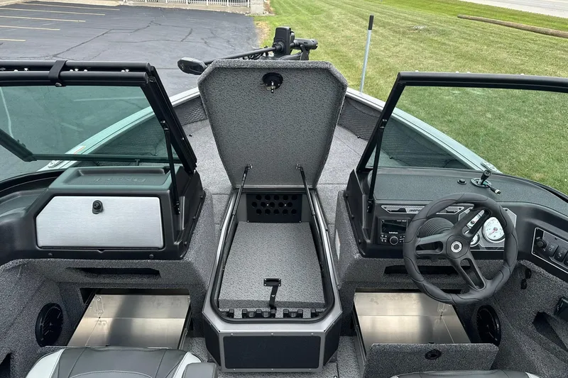 Slide: The Image of 2026 Lund 2075 Impact XS Sport boat interior with open storage and steering wheel. - 12