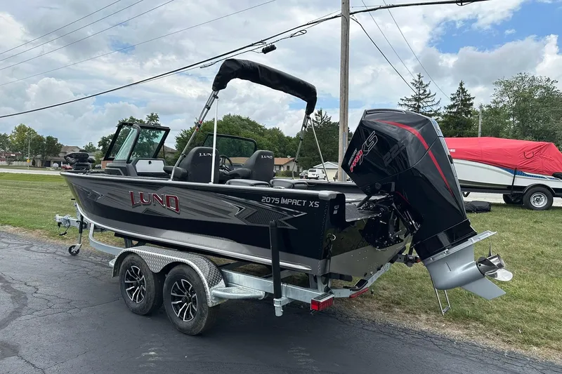 Slide: The Image of 2026 Lund 2075 Impact XS Sport boat on trailer, parked outdoors, featuring sleek design and powerful engine. - 4