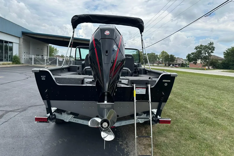 Slide: The Image of 2026 Lund 2075 Impact XS Sport boat with outboard motor and ladder, parked on grass. - 5