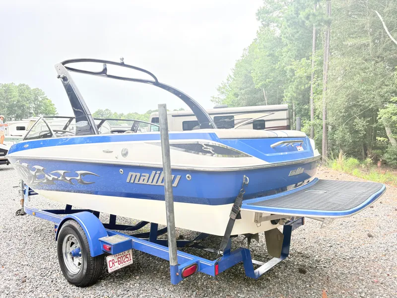 Slide: The Image of 2007 Malibu Wakesetter VTX boat on trailer, blue and white, parked outdoors. - 3
