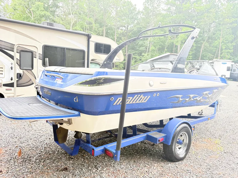 Slide: The Image of 2007 Malibu Wakesetter VTX boat on trailer, parked near RV, surrounded by trees. - 5
