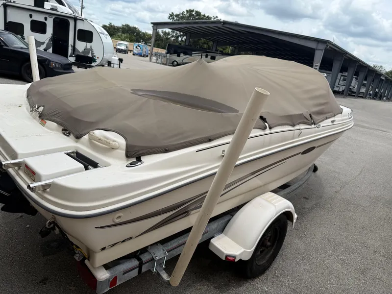 Slide: The Image of 2002 Sea Ray 176 Bow Rider boat covered on trailer in parking area. - 2