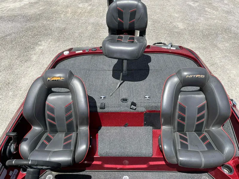 Slide: The Image of 2018 Nitro Z19 boat interior with three black and red seats on gray carpet. - 9