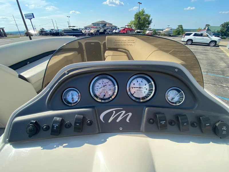 Slide: The Image of Dashboard of 2016 Manitou 25 Aurora boat with gauges and controls in a parking lot. - 14